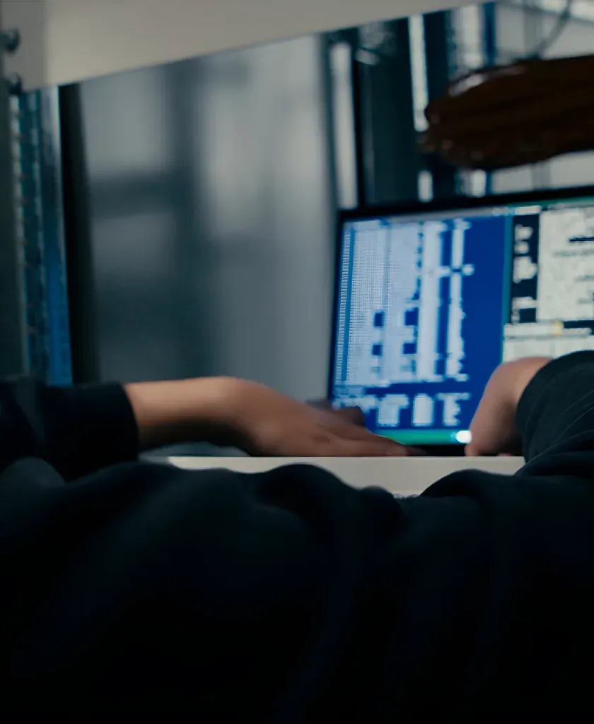 Hände an einem Laptop mit Konsolenausgabe, dahinter die Schränke im Rechenzentrum